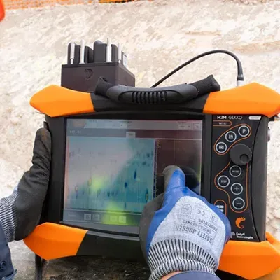 Técnico empleando ultrasonido industrial al aire libre para la detección de grietas en tuberías y estructuras