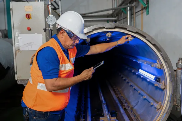 Técnico usando luz ultravioleta para ensayos no destructivos por partículas magnéticas o líquidos en un tubo.