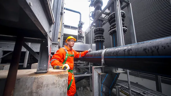 Técnico realiza mantenimiento predictivo en un sistema de tuberías industriales complejas de una planta.