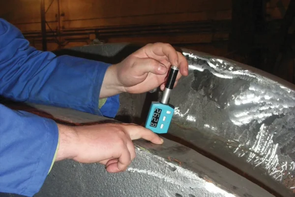 Ingeniero aplicando un ensayo de dureza en metal con el dispositivo portátil Equotip Piccolo 2